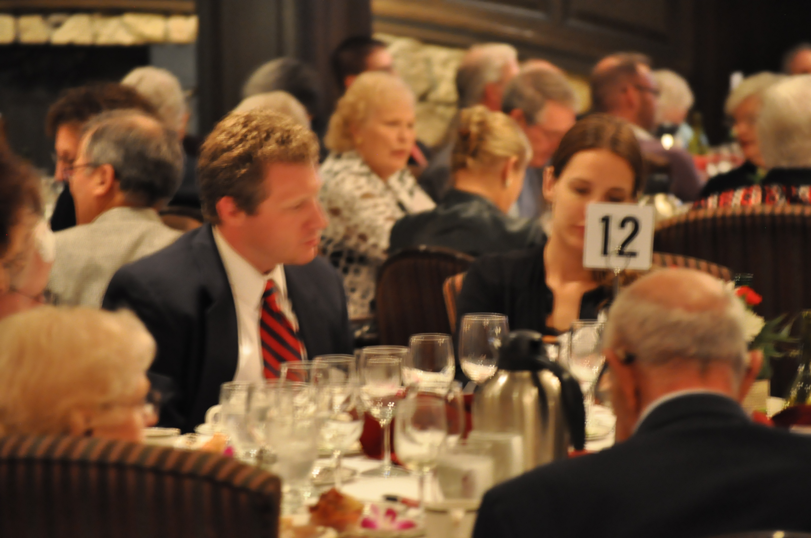 People at a table eating and listening during the Benefit Dinner
