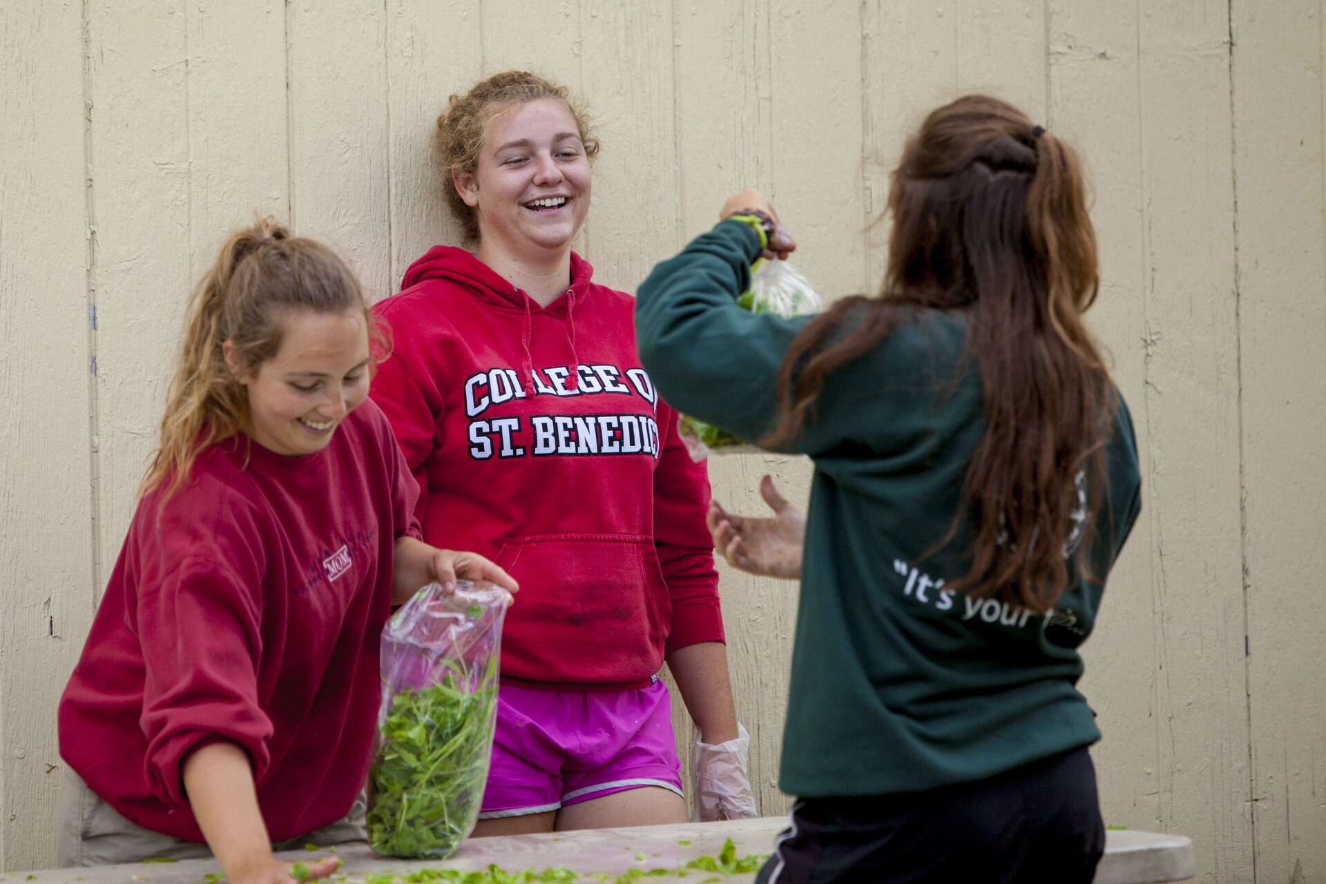 students holding bag of lettuce 