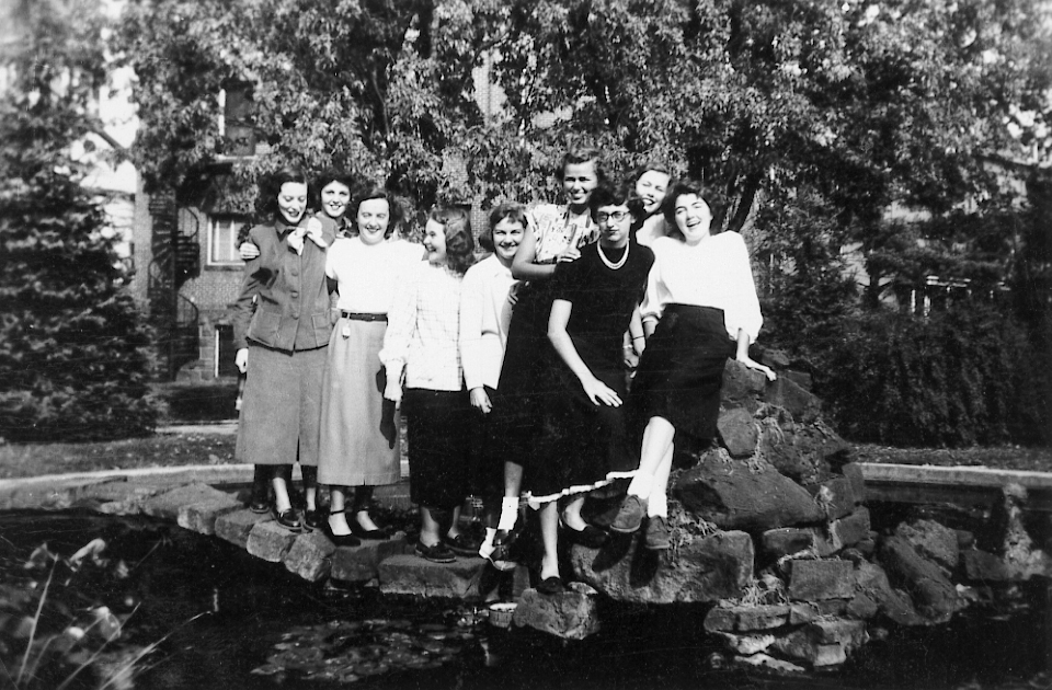 Group standing by pond with a woman sitting on the rocks.