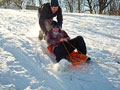 A sledder getting a push down the hill by another person
