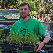 Con Brady holding a flat of prairie plants to be transplanted