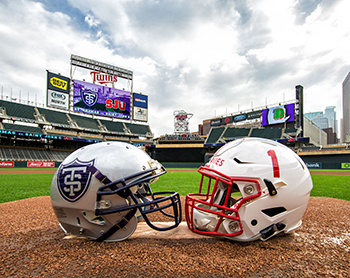 Photo of a UST and SJU football helmet facing each other on Target Field