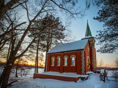 A small brick chapel build along a lake shore photographed in the winter