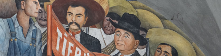 A mural depicting a group of people, including a man in blue overalls and a large hat, another man in a wide-brimmed hat and red shirt holding a red banner, and others wearing sombreros. The scene reflects a historical or social gathering.