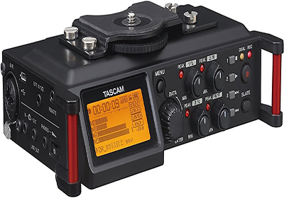 A Tascam audio recorder with various control knobs and a digital display screen showing recording settings in orange. The device has input/output ports on its sides and a mounting bracket on top.