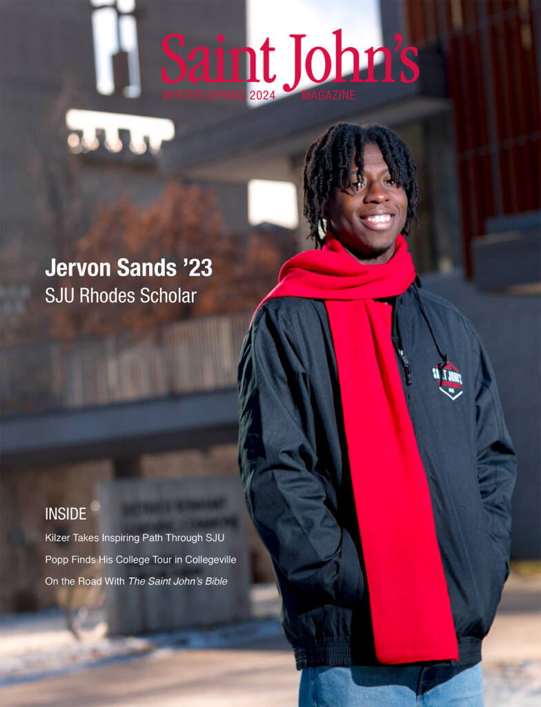 A young person stands smiling in a Saint John's University jacket and a red scarf. The background shows a campus scene. The cover text mentions Jervon Sands as an SJU Rhodes Scholar. The magazine is titled "Saint John's" Winter/Spring 2024.