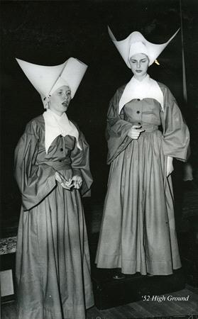 Two women dressed as nuns wearing traditional habits, including distinctive large white headdresses, pose in front of a dark backdrop. One is speaking, while the other looks down. The text in the corner reads, "'52 High Ground.