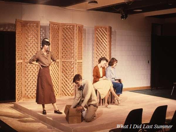 Four people are on a stage set for a play. One stands wearing a hat and suit, while the others sit, reading. A man is crouched near a box. The background has wooden lattice panels. Text in the corner reads, "What I Did Last Summer.