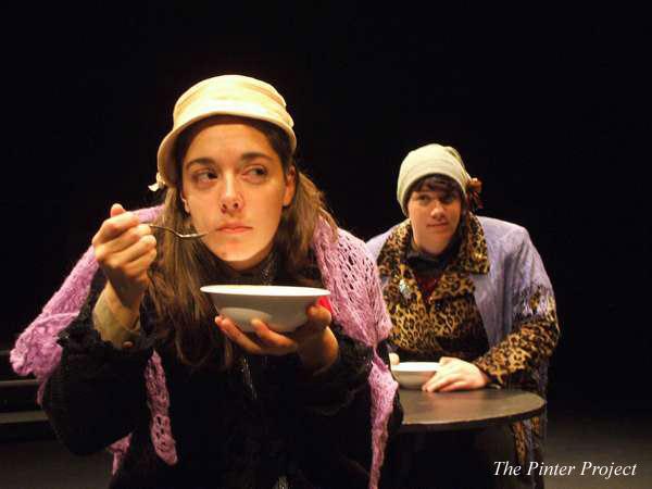 Two actors on stage perform a scene. The person in the foreground wears a beige hat and purple shawl, eating from a bowl. The other, in the background, wears a gray hat, leopard print coat, and looks on with curiosity. Text reads "The Pinter Project.