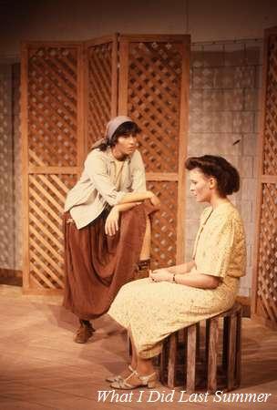 Two actors perform on stage. One stands, leaning on a wooden crate, and the other sits on a crate, both in period costumes. A lattice backdrop is behind them. Text at the bottom reads, "What I Did Last Summer.