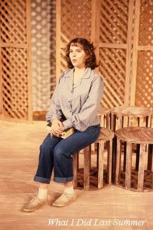 A person with short hair, wearing a blue blouse and jeans, sits on a round wooden stool on a stage. The backdrop features a lattice pattern. The text "What I Did Last Summer" appears at the bottom of the image.