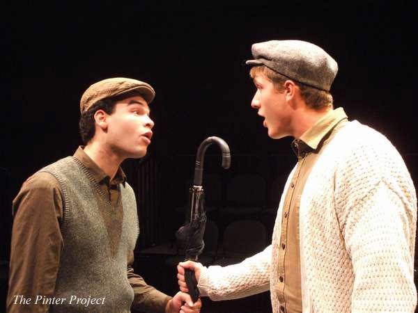 Two people in caps and vintage-style clothing face each other dramatically, holding an umbrella. They're engaged in an intense conversation on a dimly lit stage. Text reads "The Pinter Project" in the corner.