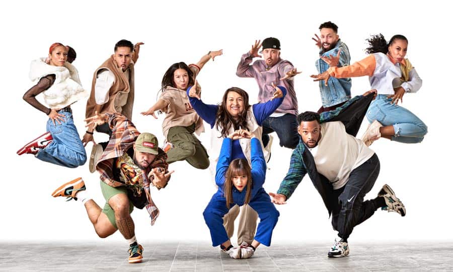 A diverse group of 10 people energetically pose mid-air in a jumping formation against a white background. Each person exhibits a distinct style with expressive and dynamic movements, showcasing a sense of unity and exuberance.