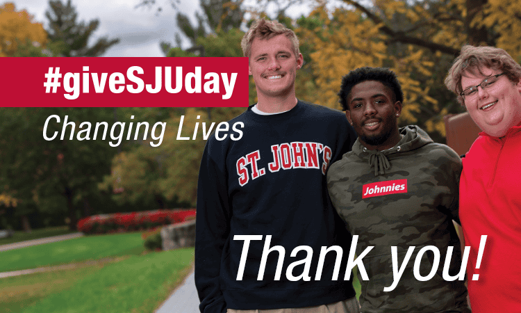 Three people stand together outdoors, smiling at the camera. The text says "#giveSJUday Changing Lives Thank you!" Two of them are wearing "St. John's" and "Johnnies" apparel. The background features trees and a pathway.