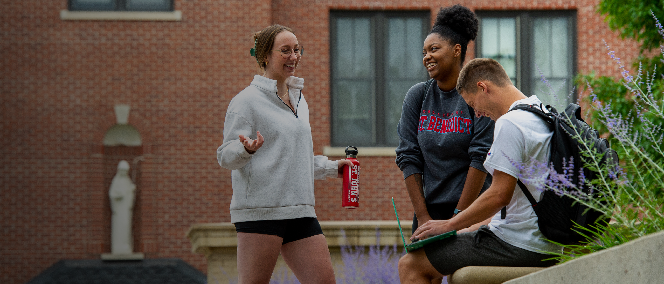 Three students sharing a conversation outside on the College of Saint Benedict campus.